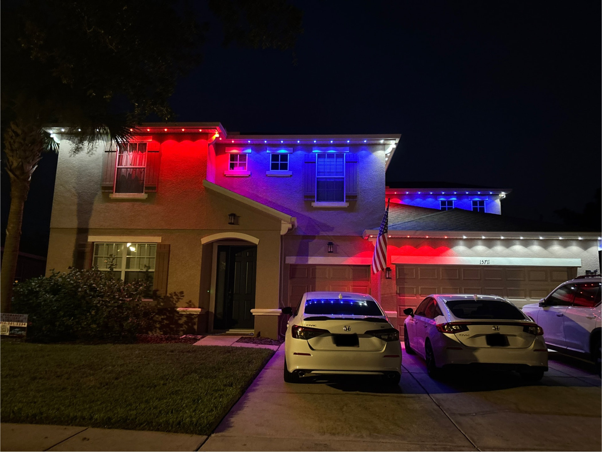 Two-story home lit in patriotic red, white, and blue permanent lights